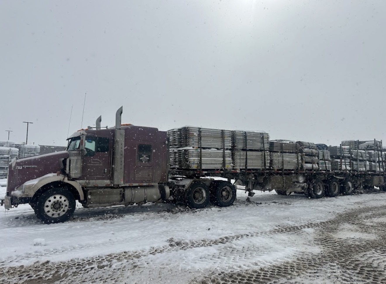 Kenworth flatbed with scaffolding load parked in the yard during a snowstorm